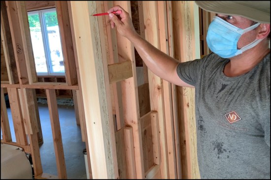 The 1-by padding was later removed, planed as necessary, and reinstalled before drywall. In the photo, lead carpenter Ryan Labrenz points to the planned edge of drywall.