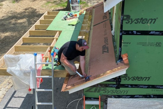 Copper flashing is run up the rake edge of the roof and at the ends of the gutter.