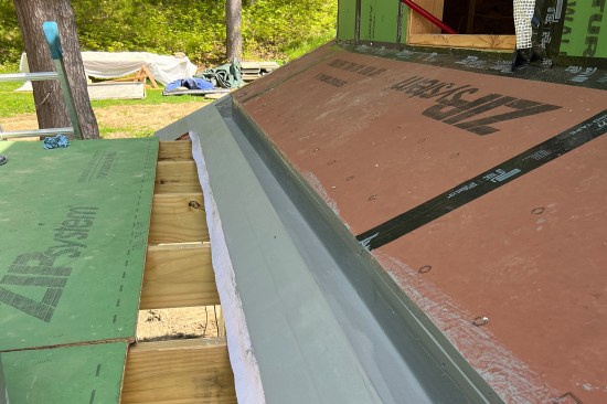Installing the Acrylabs liner, the gray-colored two-coat base with reinforcing fabric was first applied to the trough and downslope portions of the gutter, covering the copper edge flashing.