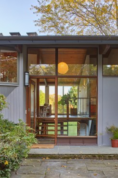 Signature “deck house” features such as exposed beams, a tongue-and-groove ceiling, an open floor plan, and lots of glass help connect the home to its scenic backyard, both from the interior and from outside the home’s front elevation.