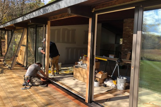 Crew members install two new Marvin Ultimate sliding patio doors flanking a fixed glazed center panel.