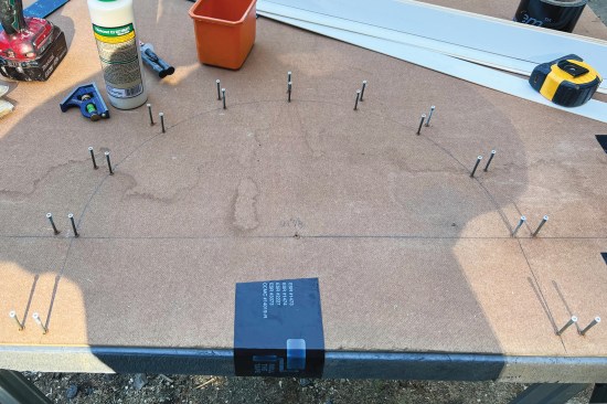 To fabricate the arch top, the inside and outside radii of the new extensions were marked on a piece of sheet stock. A series of finish screws were then set along the lines.