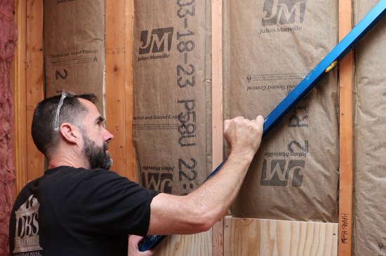 The author checks for plane by spanning a 6-foot-long level across an existing studwall.