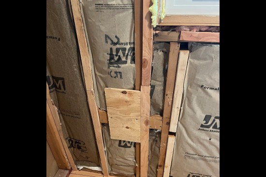 Existing studs shimmed to plane out wall. Sistered studs, shown on the right-hand side of photo, also used to plane out the wall.