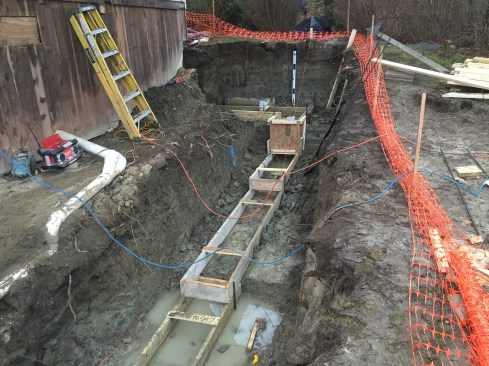 Working in soggy, heavy clay soils, the crew formed up footings for a new concrete retaining wall and foundation to support the new addition.