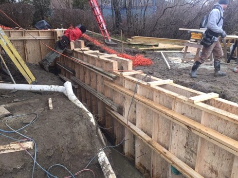 Wooden forms in place for a new foundation wall, designed to hold back new fill as well as support the remodeled house structure. Because of zoning restrictions, the new structure had to stay within the footprint of the existing house.