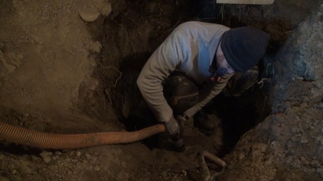 Chris vacuums water out of the excavation. After a sump pump got clogged with silt, the crew switched to a Ridgid shop vacuum, which handled the muddy water with ease.