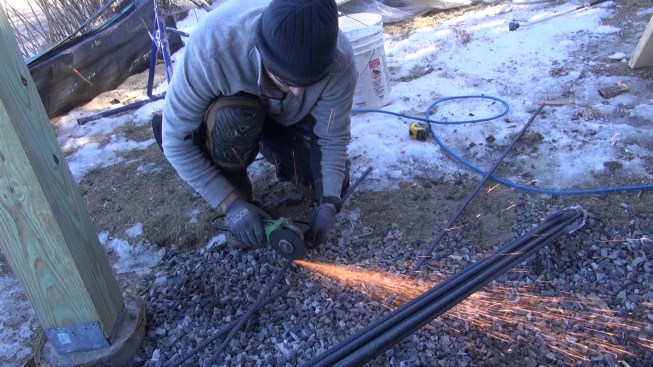 Chris cuts pieces of half-inch reinforcing steel to length with an abrasive grinder wheel.