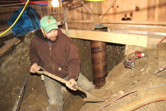 Shane digs a shovelfull of soil for backfilling the base of the newly set Sonotube.