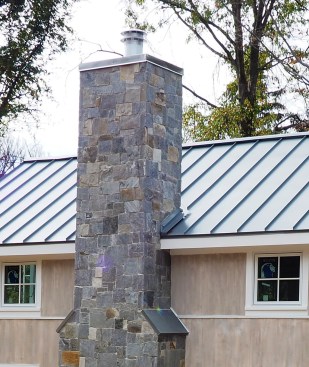 Roof intersection for a framed chimney clad with adhered stone.