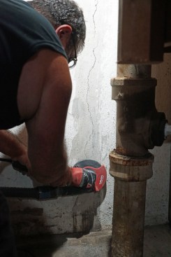 Toby Bonilla of Great Lakes Builders grinds the surface of the foundation wall to ensure a strong bond with an epoxy dam material.