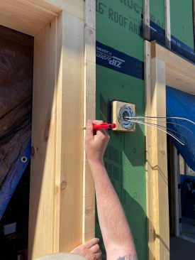 With the trim installed, the crew employs a story pole to align clapboards.