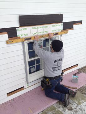 After positioning the window in the opening, Manny checks the top of the window for level.