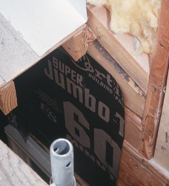 Roof-to-wall intersections create particular problems. This bad detail held up the work: The rafter placed tight to the building wall does not allow paper to slip behind it, and the flashing left by the roofers will direct water behind the stucco and into the wall if used as configured.
