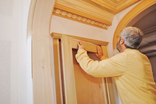 The built-up head trim hides most of the gap at the top of the cabinet. A thin strip attached to the cabinet covers the rest.