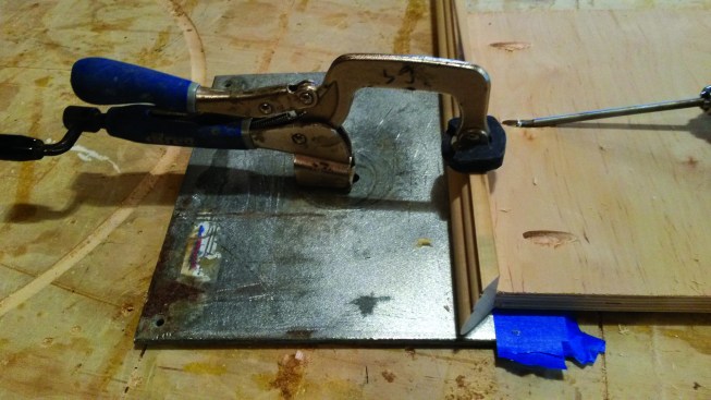 The author applies several strips of painter's tape to the plate clamp to keep the trim slightly proud of the plywood. The small excess is then sanded down flush.
