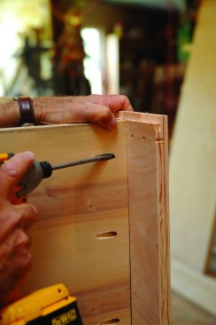 The author inserts the top of the cabinet into a shallow dado before driving the pocket screws.