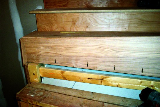 The author pocket screws stair treads to the riser above from underneath. Here the tread is ready to be tipped down and screwed in.