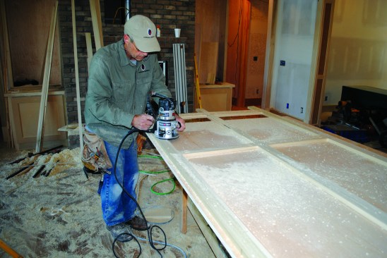 Once the face frame is assembed, the author routs a groove in the back that the panel fits into. Then decorative molding can be added around the panel on the front side.