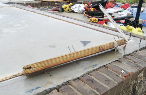 A length of sill plate was the only piece of the exterior walls that remained on the slab; the sills had been attached with rectangular cut nails.