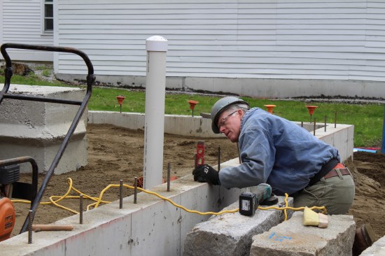 A granite capstone, reclaimed from the existing foundation, lined the remaining foundation perimeter; here, the masonry sub maps out
the rebar locations and angles to accurately line up boring holes.