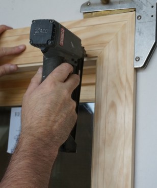 Finish nails along the inside edge secure the casing in place. Note that the nailer is held with the nose perpendicular to the edge to keep the nail heads parallel to the grain.