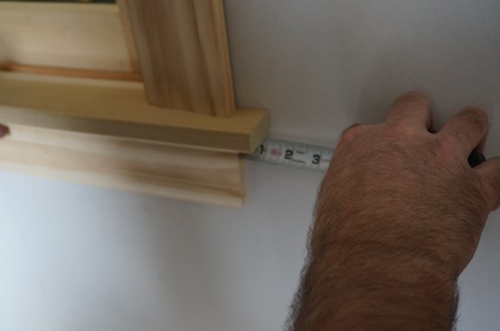 The end of the apron should line up with the outside edge of the casing above. Here, the author matches the measurement from the end of the stool horn.