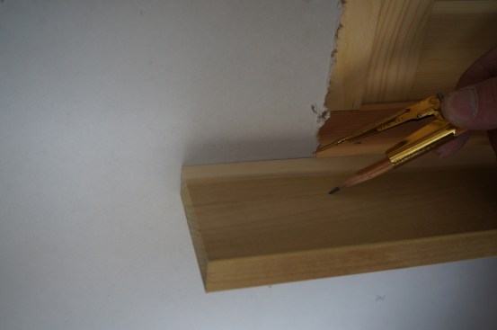 Holding the point of the dividers against the wall, scribe a line for the parts of the stool that extend to either side of the window opening.