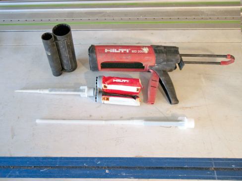 The author's crew used a two-part epoxy from Hilti that is installed with a proprietary gun. The long nozzle on the Hilti gun was helpful for injecting the epoxy through the thick window bucks.