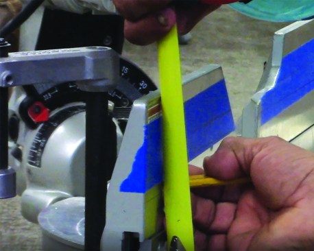 When the crown molding lands within an inch of the tops of the cabinet doors, an out-of-level condition can often be dealt with by rolling the crown. For this 2 1/2-inch crown, draw lines on the miter saw fence at 2, 2 1/4, 2 1/2, and 2 3/4 inches (see illustration and photo).