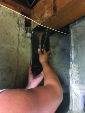 He dry-fit the bracket and removed any unevenness in the concrete so that the bracket sat perfectly flat against the foundation wall.
