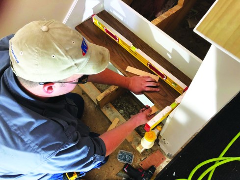 After spreading carpenter’s glue on the back edge of the tread where it will butt into the riser, he slips the tread into place.