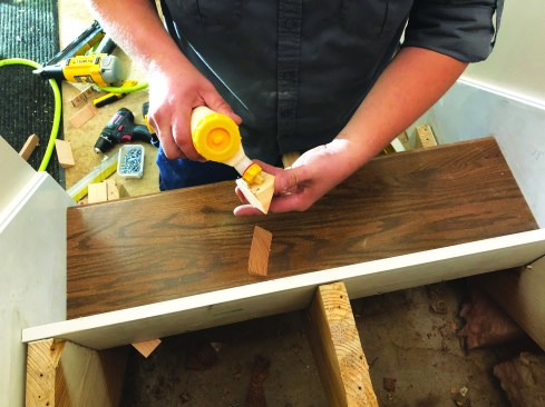 The author fashions triangular blocks from 2x4 stock to help stabilize the tops of the risers by joining them to the underside of the tread above. He spreads a heavy layer of carpenters glue on the adjacent right-angle sides of the block.