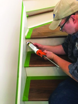 The author installs shoe molding around the landing and caulks all the painted seams.