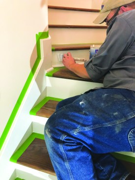 He puts puts a finish coat of paint on the skirts and risers.