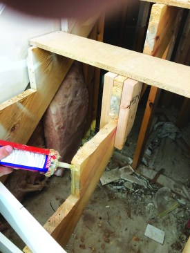 Back at the staircase, he applies a liberal amount of construction adhesive to the stringers.