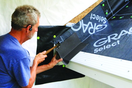 Next, the kickout flashing—which is also the first piece of step flashing—is nailed in place.
