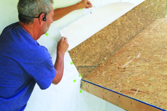 The first step to installing the flashing is cutting and lifting a flap of WRB to access the sheathing at the roof-wall intersection.