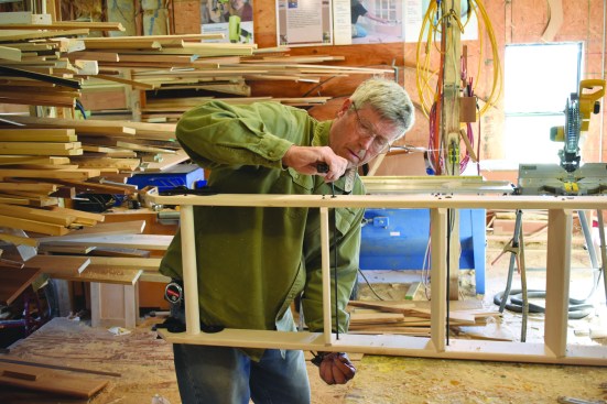 After drilling holes, he installs the spreader rods, which are held at each end with cap nuts.