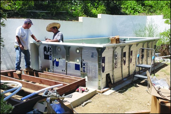 Figure 1. A work crew assembles a modular Endless Pool kit. The kit’s galvanized steel panels are bolted together, then insulated with rigid insulation.
