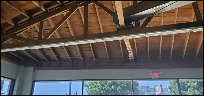 The 2-by rafters transition from a bowstring truss to a ledger above a wall-to-wall storefront entry in the showroom area.