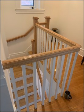 The finish stair from the second floor shows the continuity of the handrail. Code allows the handrail to be interrupted at a newel for winders, as it is here, where the newel rises to the upper-floor guardrail height.