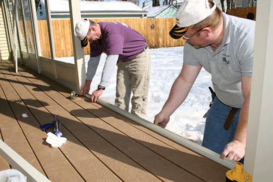 After bedding the base track in caulk, we screw it to the decking, then drill weep holes 3 inches from the ends and 16 inches on-center.