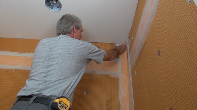 Boucher places a pre-creased strip of Kerdi-Band into the prepared corner joint.