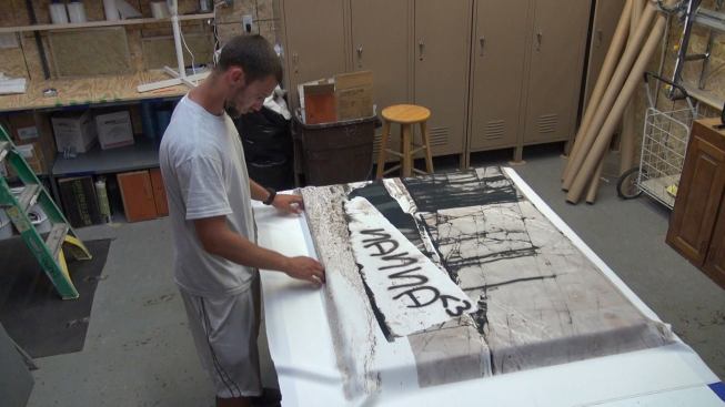 Fitting the screen-printed cloth covering over the “REVRB” insulated panel. Cloth used for this purpose must be rated to allow the passage of sound waves, so that the sound energy can penetrate the panel surface and be absorbed by the rock wool insulation interior.