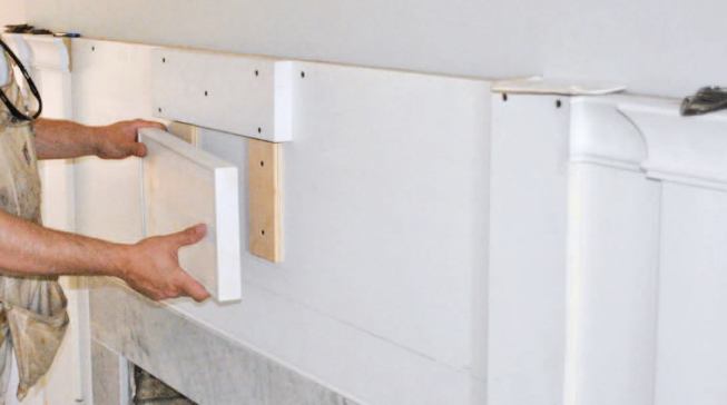 The center bump-out is two separate pieces and sits a little proud of the pilasters; the bottom piece is wrapped with 1/4-inch MDF and hangs from the two pieces of plywood backing.