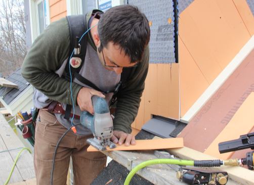 Pollard uses a jigsaw to cut a matching roof angle onto a shingle.