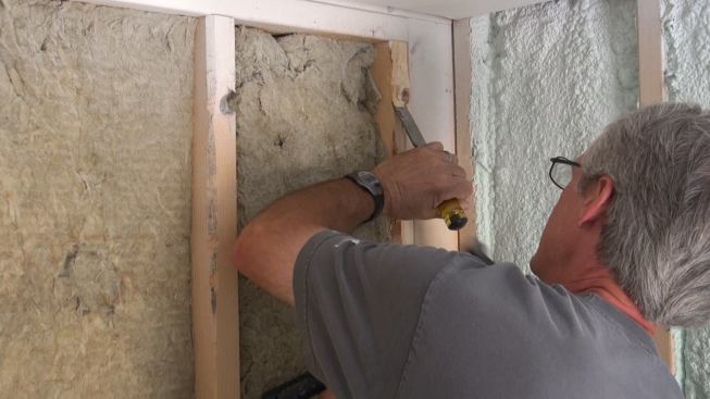 Boucher chisels away a stubborn knot that's contributing to a high spot in the wall framing.