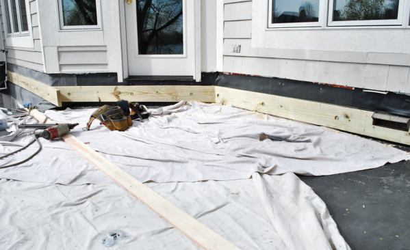 A pressure-treated deck ledger supports the inboard end of the new joists.