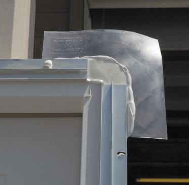 The upper corners are protected by a pair of flexible corner flashings bedded in the sealant. These flashings also help build out the top of the door to match the base, keeping the unit plumb after installation.